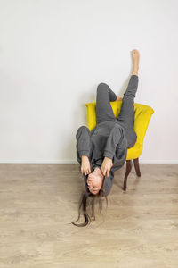 Women sitting on chair against wall