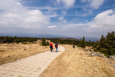 Rear view of men walking on mountain against sky