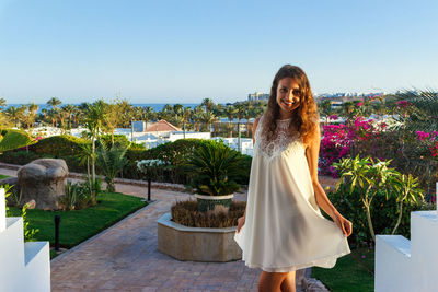 Portrait of smiling young woman standing against sky