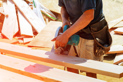 Midsection of carpenter working on wooden plank