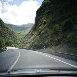 Road amidst trees seen through car windshield