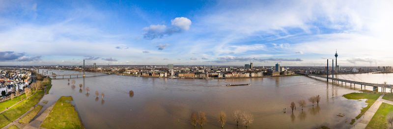 Panoramic view of city by river against sky