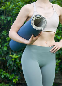 Midsection of woman standing against plants