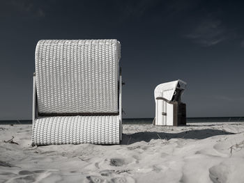 Hooded beach chairs on sand against sky