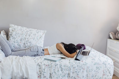 Girl taking nap with wireless technologies on bed at home