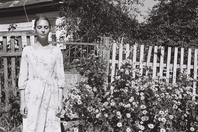 Portrait of young woman standing by plants