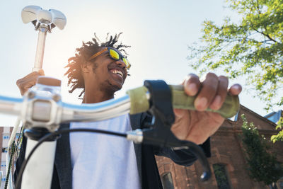 Low angle view of man with bicycle standing against sky