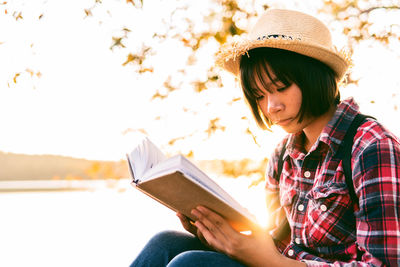 Young woman looking away while sitting on book