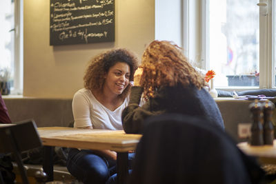 Friends talking while sitting at table in restaurant