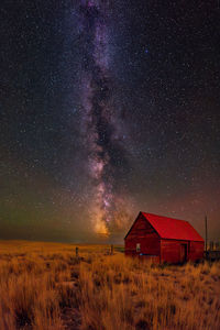 Milky way galaxy behind old red barn 