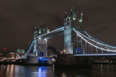 Illuminated bridge over river at night