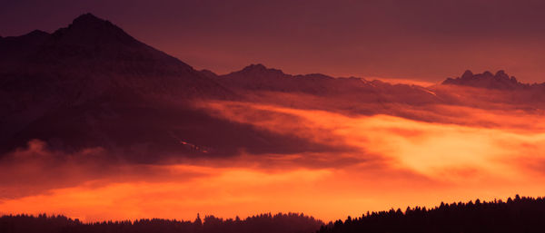 Scenic view of silhouette mountains against orange sky