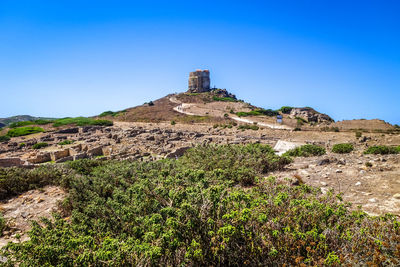 Built structure on landscape against clear blue sky