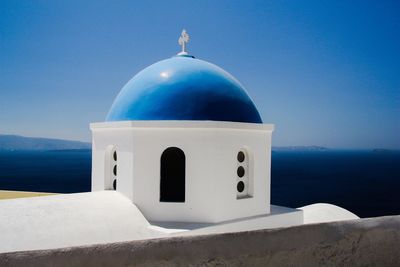 Chapel by sea against clear blue sky at santorini