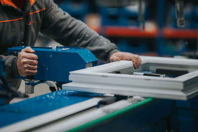 Midsection of mature man using equipment in factory