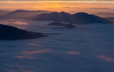Scenic view of dramatic sky over mountains during sunset