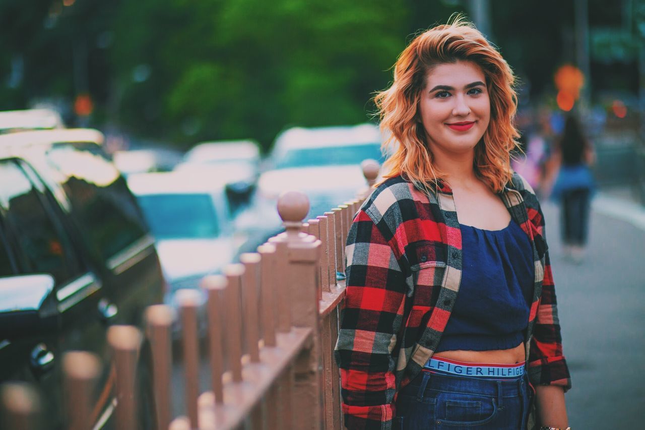 one person, young adult, portrait, looking at camera, lifestyles, standing, real people, young women, smiling, car, focus on foreground, motor vehicle, leisure activity, transportation, casual clothing, city, front view, waist up, hair, beautiful woman, hairstyle, outdoors
