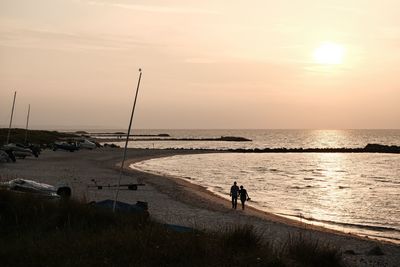 People on beach against sky during sunset