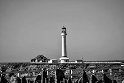 Lighthouse by building against clear sky