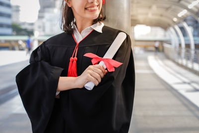 Woman holding a smiling while standing against the wall