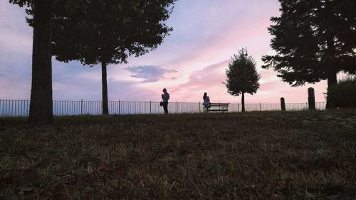 People standing on field against sky during sunset