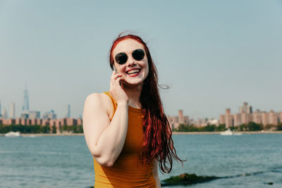 Portrait of smiling young woman against sky