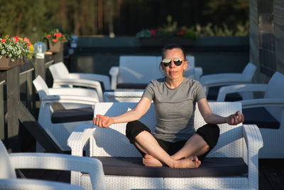 Mature woman meditating while sitting on sofa