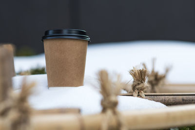 Close-up of disposable coffee cup on snow