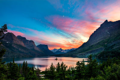 Scenic view of lake by mountains against sky during sunset