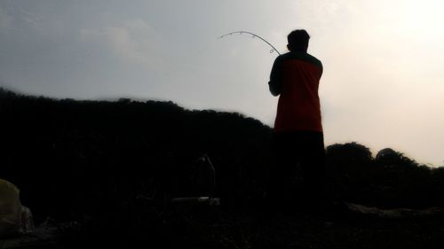 Rear view of silhouette man standing on field against sky