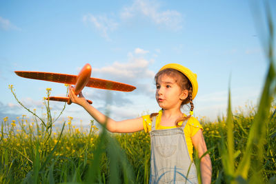 Cute girl standing on field against sky