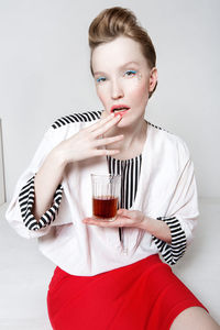 Portrait of beautiful young woman drinking glass