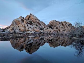 Reflection of rocks in lake against sky