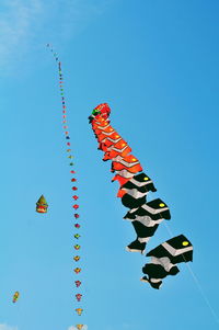 Low angle view of flags hanging against clear blue sky