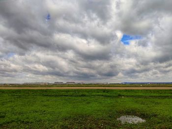 Scenic view of field against cloudy sky