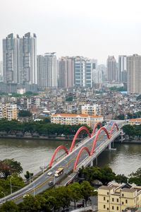 Bridge over river amidst buildings in city against sky