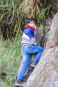 Portrait of teenage boy climbing on rock in forest