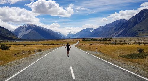 Rear view of woman walking on road against mountain range