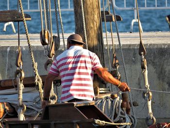 Rear view of man working on boat