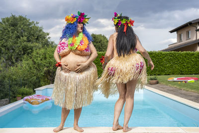 Traditional dancers standing by swimming pool against sky