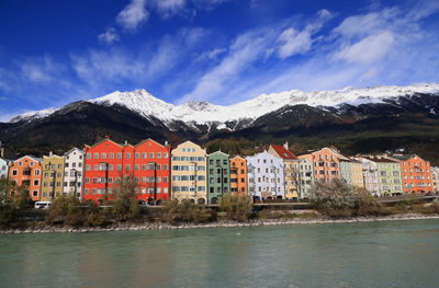 Buildings by river against sky