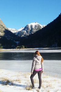 Rear view of woman standing on snow covered land against sky