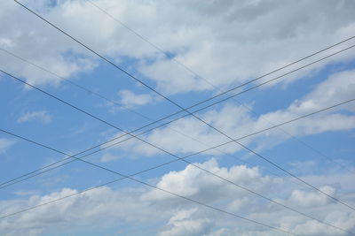 Low angle view of cables against cloudy sky