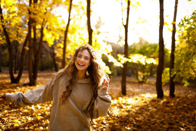 Portrait of young woman standing against trees