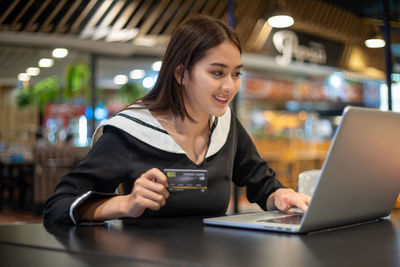 Young woman using mobile phone while sitting on table