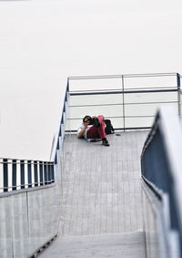 Low angle view of young woman on staircase against sky