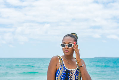 Portrait of young woman wearing sunglasses against sea