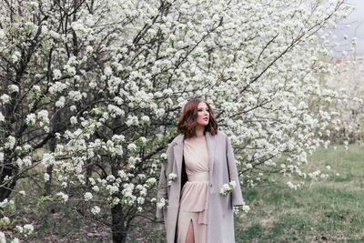 Woman standing by cherry blossom tree