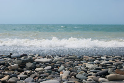 Pebbles on beach against clear sky