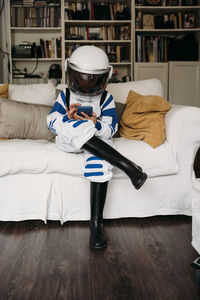 Girl wearing space costume using smart phone sitting on sofa